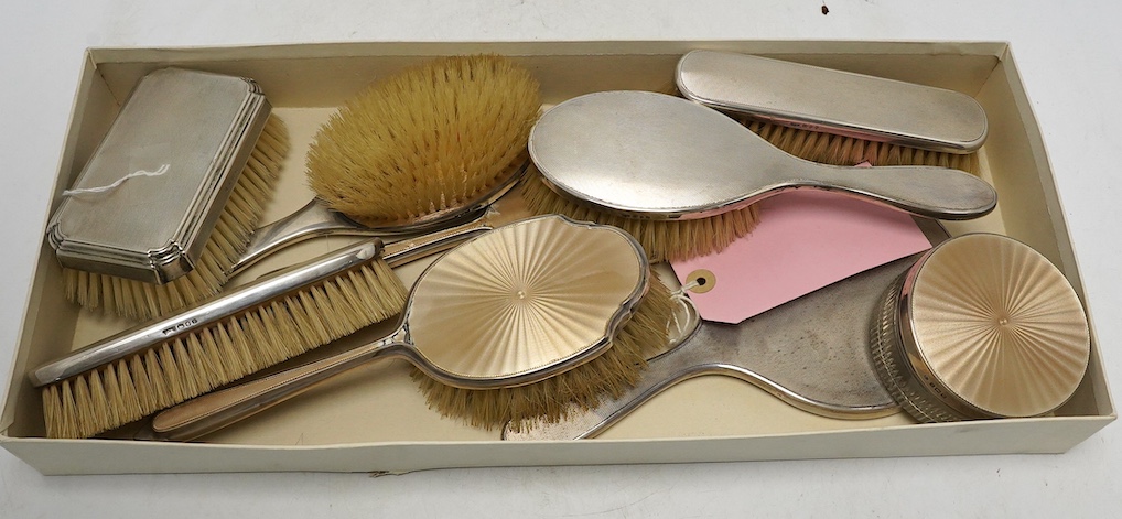 Nine assorted mid 20th century silver mounted dressing table items including a hand mirror, brush and powder jar with enamel, jar diameter 86mm. Condition - poor to fair